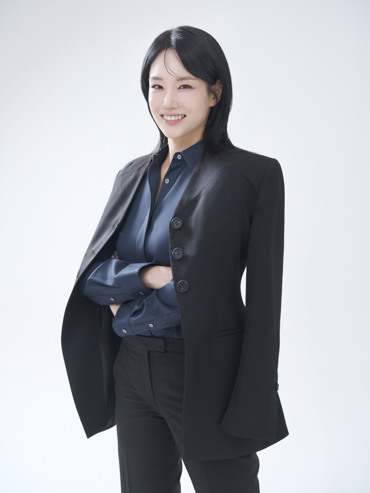 검은 재킷을 어깨에 걸치고 팔짱을 낀 채 웃는 여성 프로필