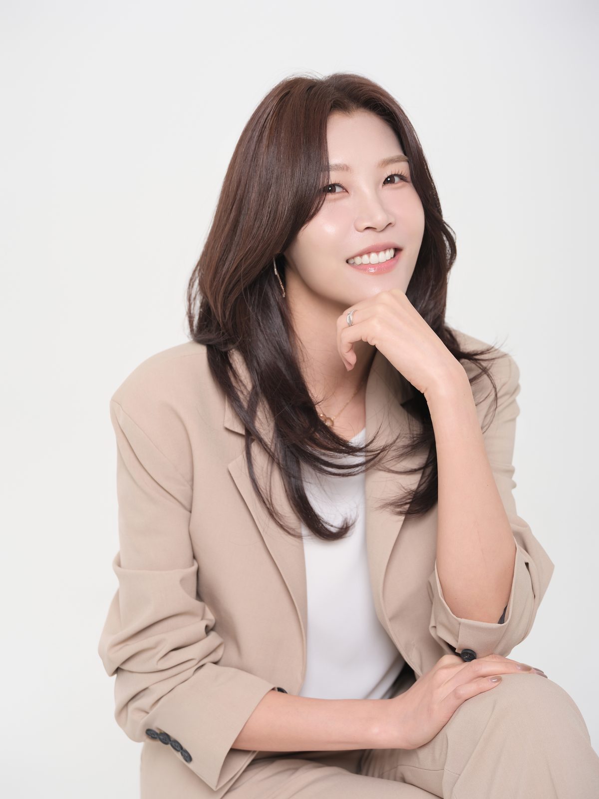 베이지 정장 차림으로 턱을 괴고 웃는 여성 대표 프로필