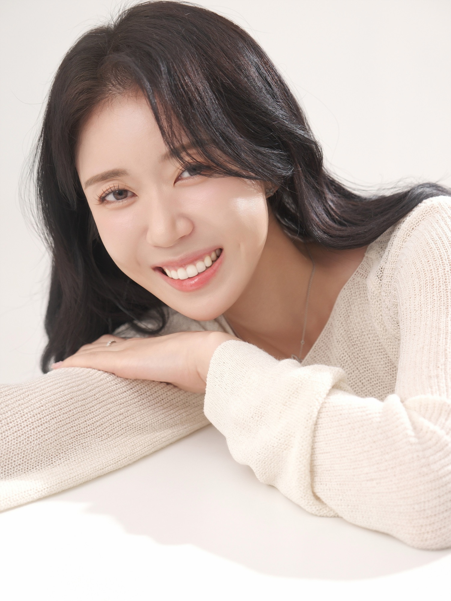 밝은 배경에서 아이보리 니트를 입고 팔에 기대어 환하게 웃는 여성 프로필