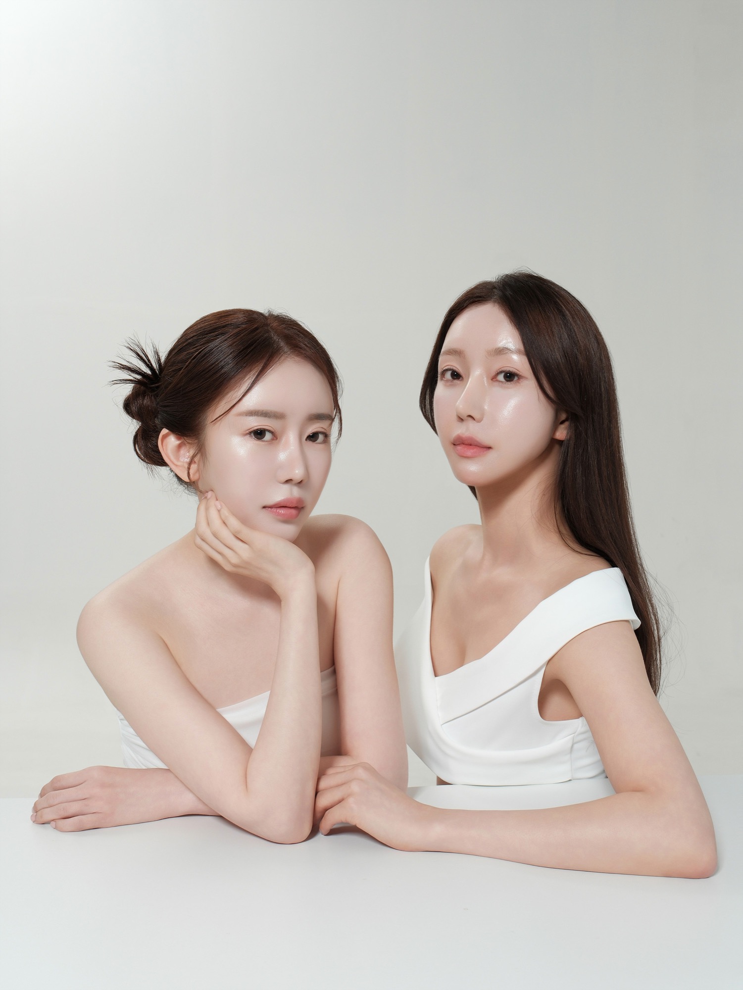 흰 배경에서 두 여성 모델이 나란히 턱을 괴고 있는 뷰티 화보