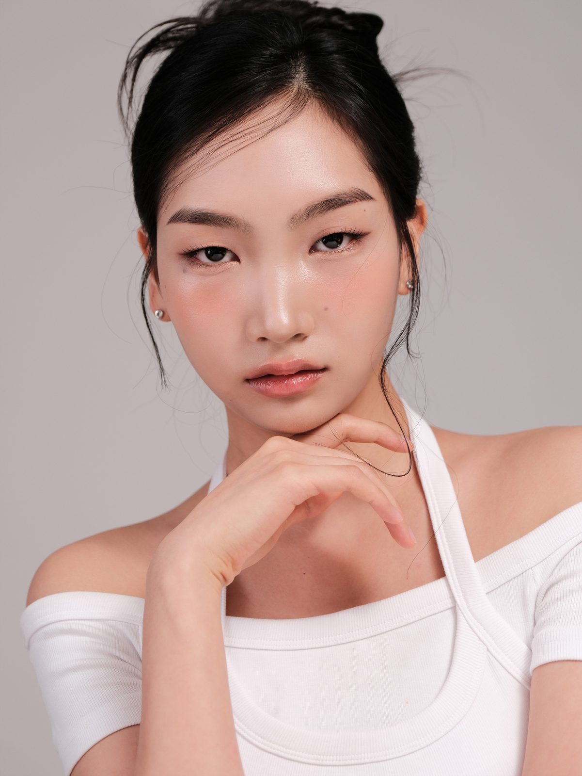 흰 오프숄더 상의에 손을 턱 가까이 둔 여성 모델 프로필
