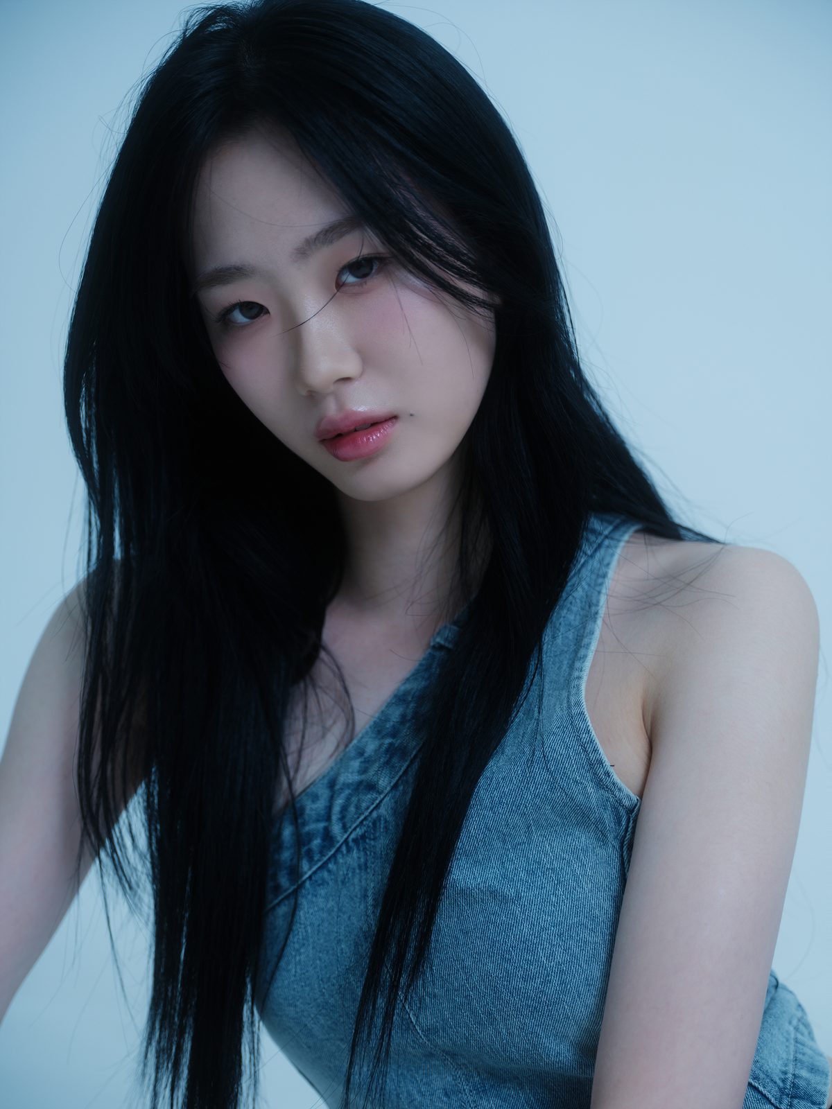 푸른 배경에서 긴 생머리로 비스듬히 앉은 여성 프로필