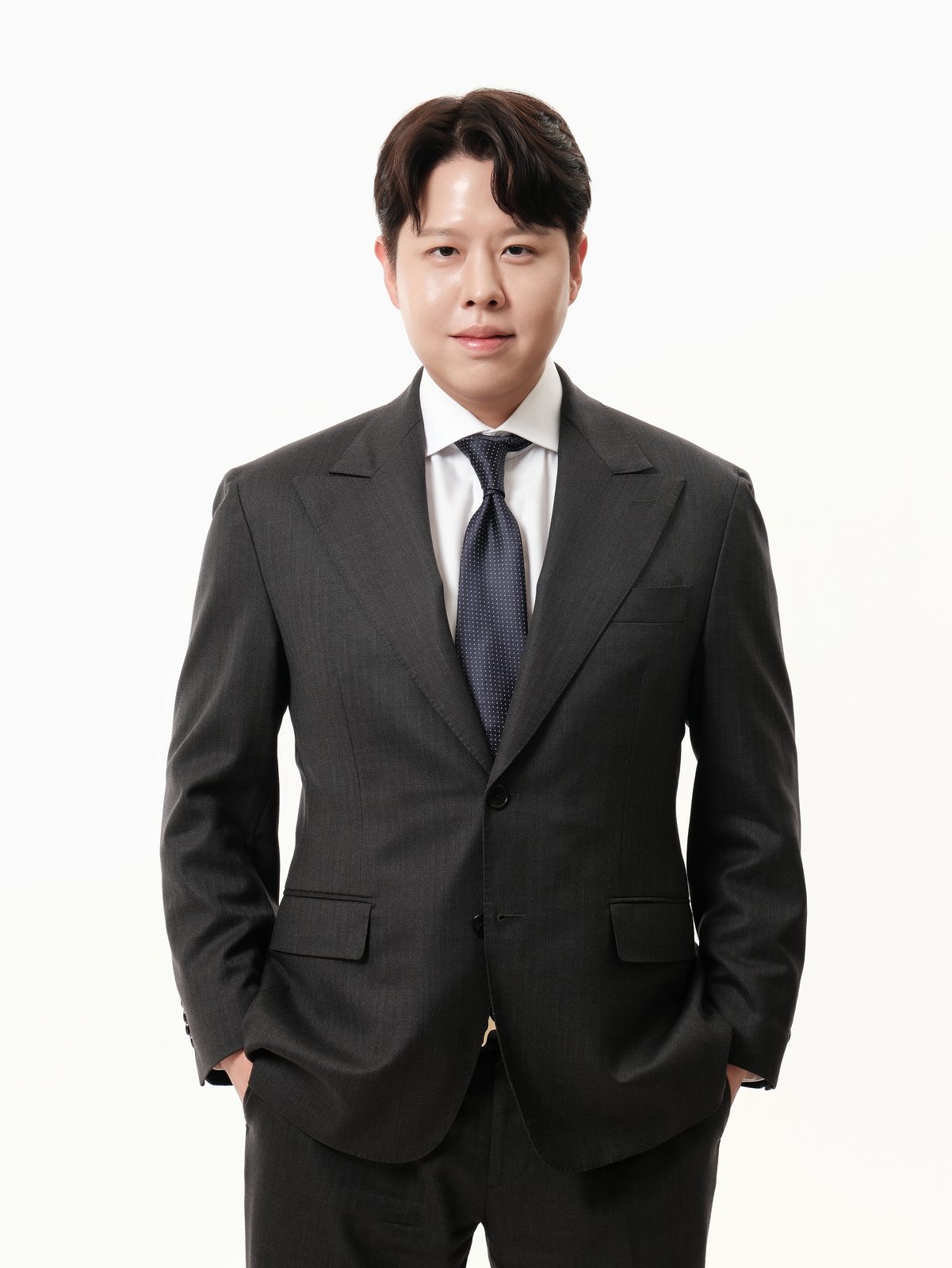 짙은 정장을 입은 남성 직원이 손을 주머니에 넣고 서 있는 프로필 사진